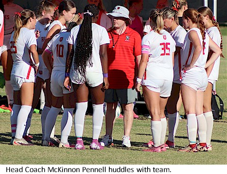Head Coach McKinnon Pennell huddles with team.
